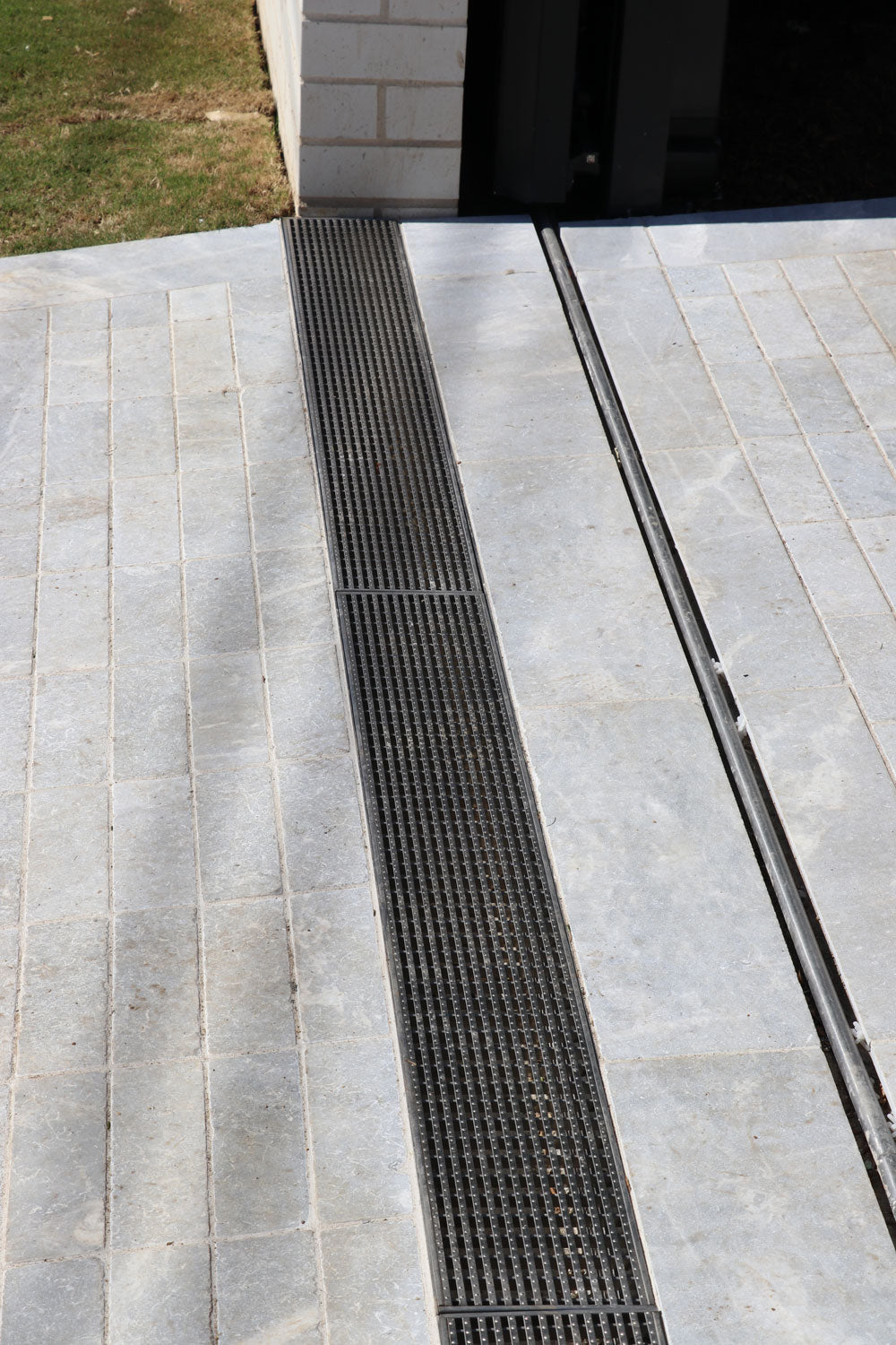 Stainless steel heel guard strip drain installed in stone-paved driveway at prestige Sydney home.