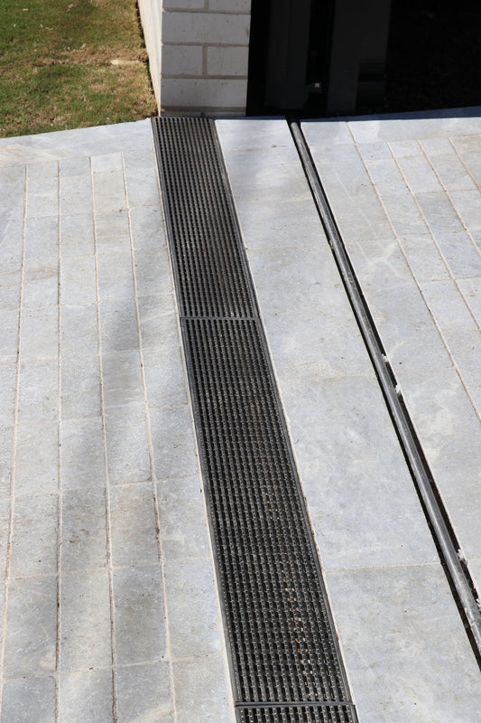 Stainless steel heel guard strip drain installed in stone-paved driveway at prestige Sydney home.